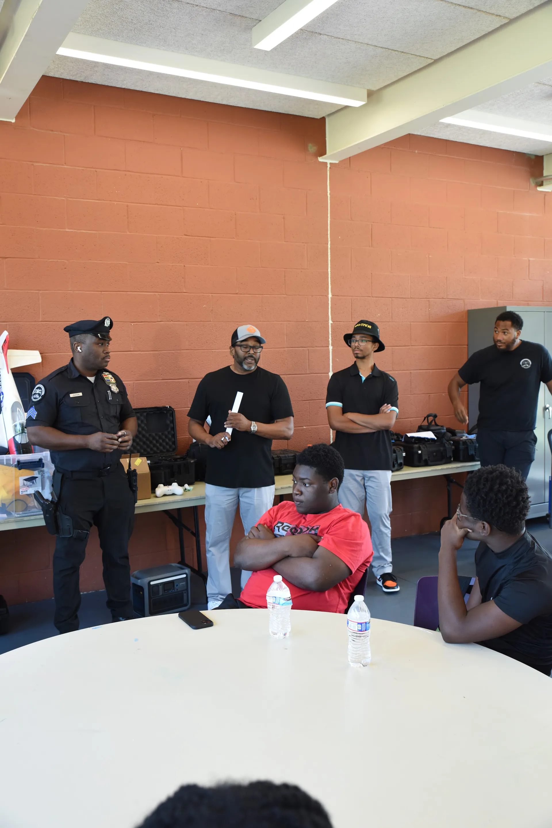 Grace3 staff and a Philadelphia Police officer with drone equipment alongside students at a table