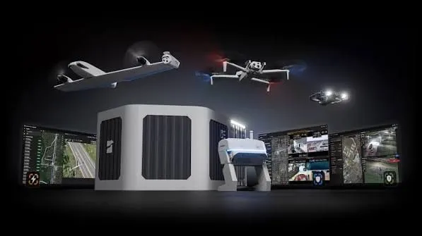 Drones in flight beside a white ground dock and operator screens