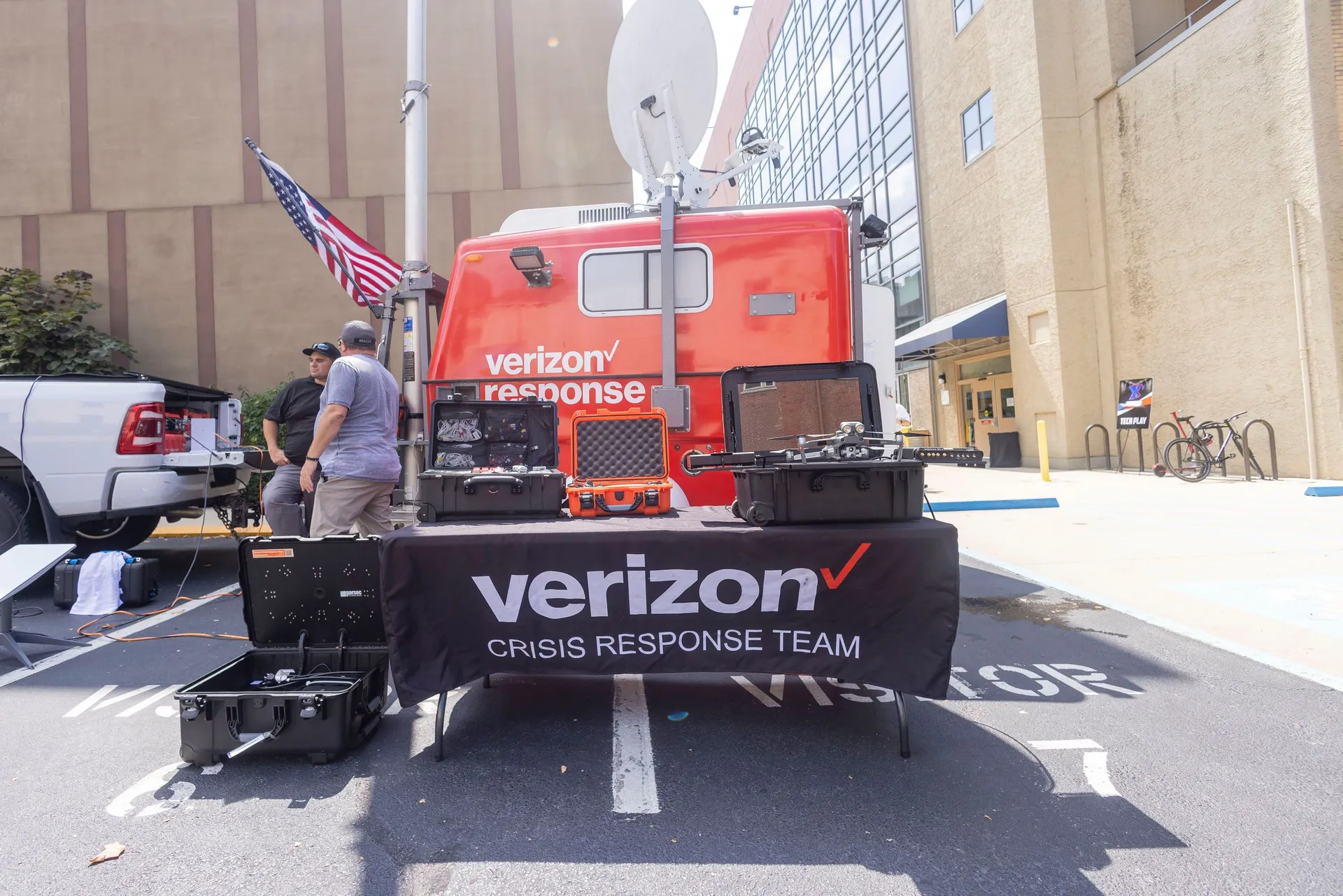 A Verizon response van, American flag, open equipment cases, and drone hardware staged on a table